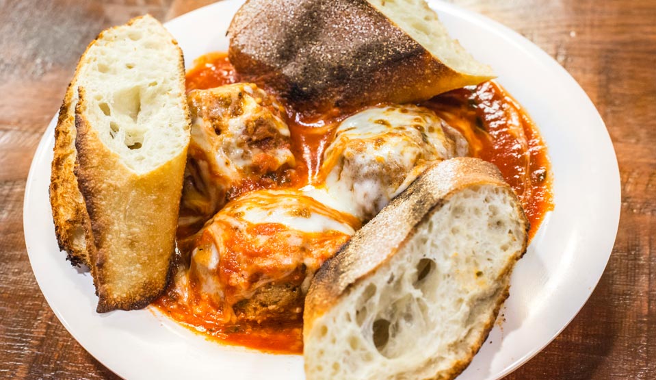 Sausage in red sauce with melted cheese and slices of Italian bread.