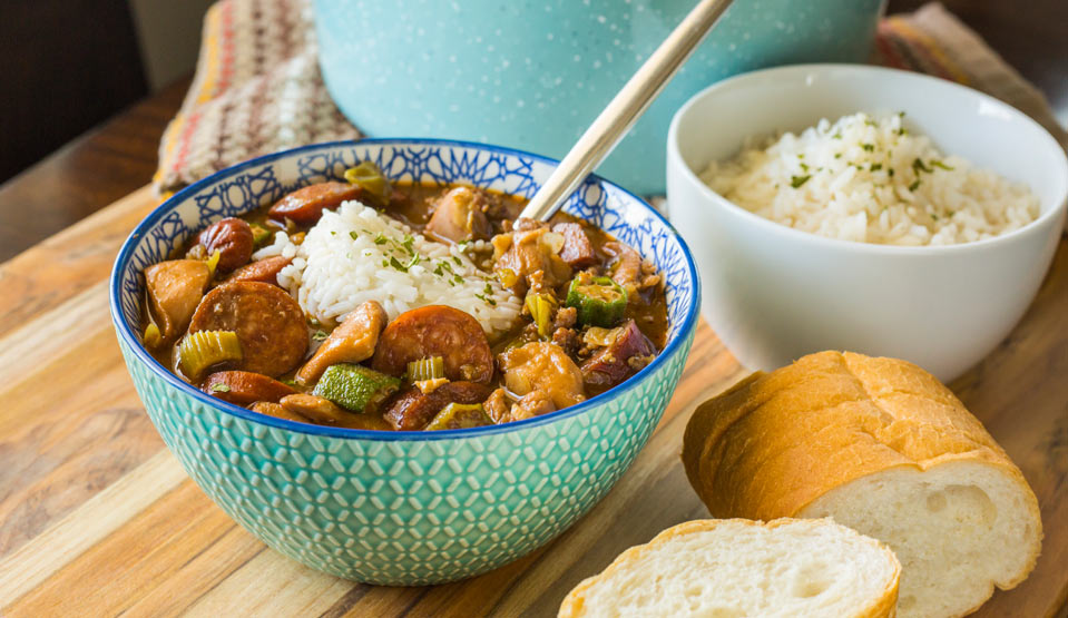 Louisiana Chicken & Sausage Gumbo in bowl with side bowl of rice and sliced bread.