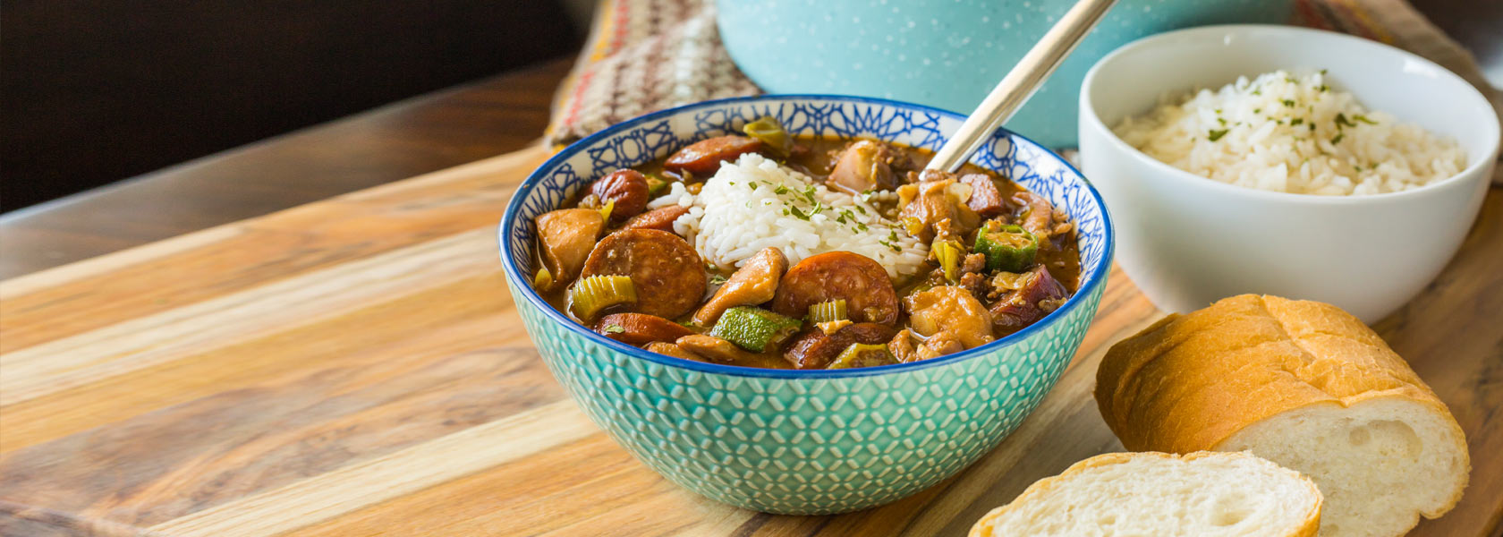 Louisiana Chicken & Sausage Gumbo in bowl with side bowl of rice and sliced bread.