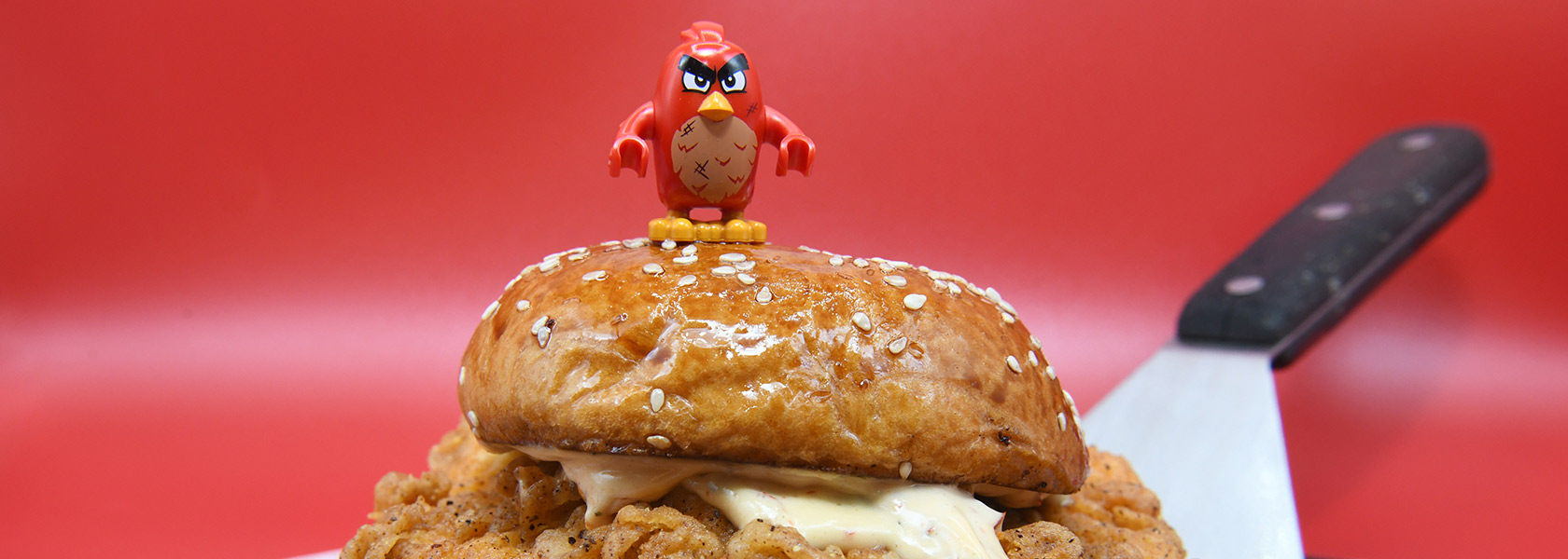 Angry bird figurine standing on top of Cluck Norris chicken sandwich