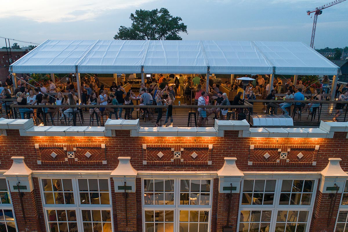 Drone view of crowd under white canopy on the rooftop at Budd Dairy Food Hall in Columbus, Ohio.