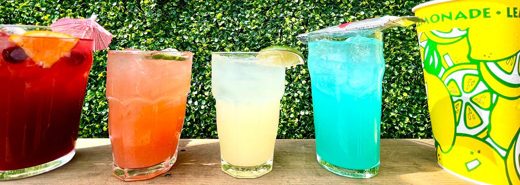 Array of colorful beverages on a shelf in front of a hedge