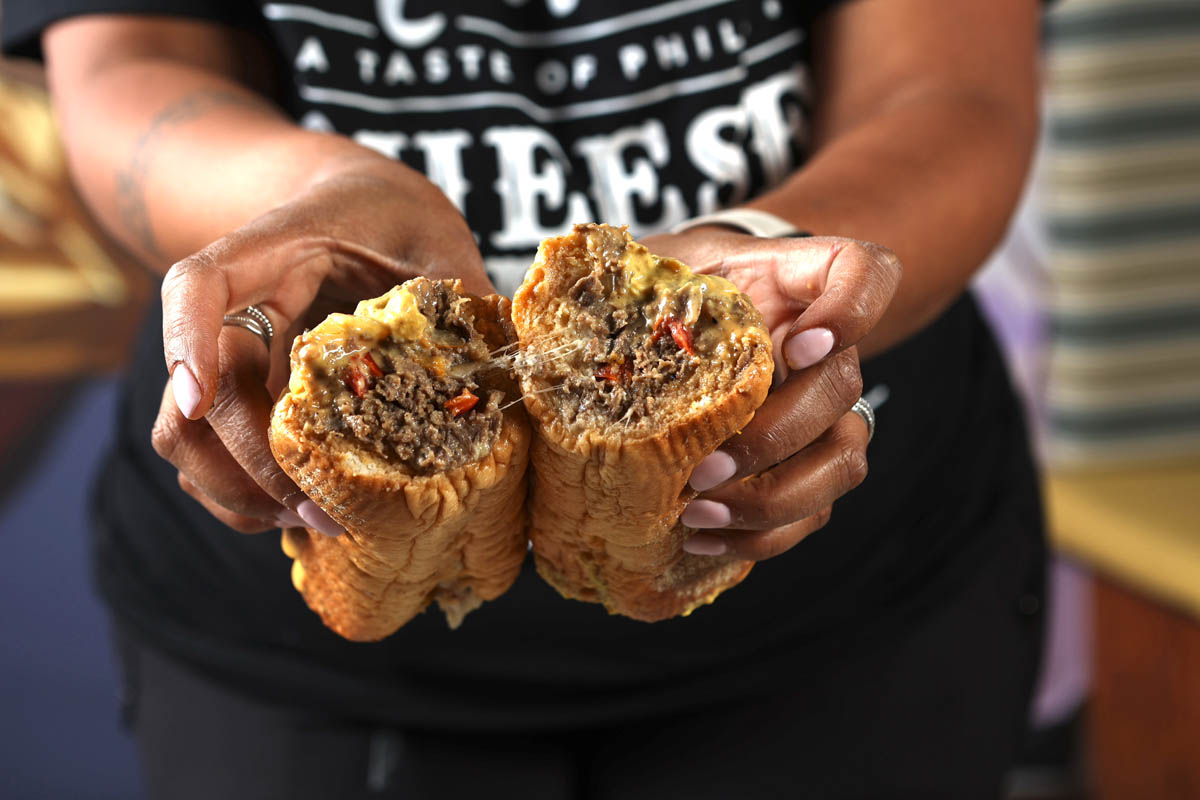 Hands holding a split Marlow's Cheesesteak