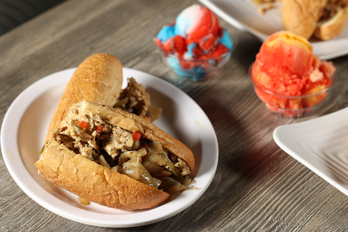 Philly Chicken Cheesesteak sandwich on plate with bowls of Water Ice made by Marlow's Cheesesteaks in Columbus, Ohio.