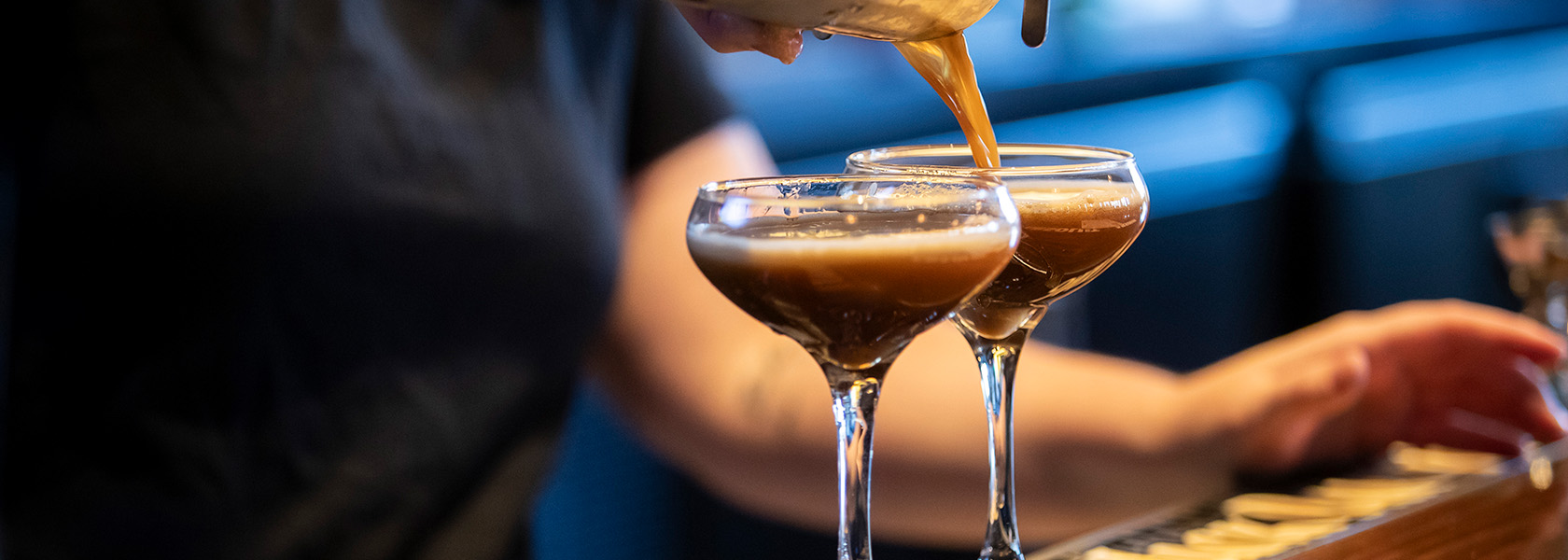 Bartender pours two espresso cocktails into coupe glasses at Budd Dairy Food Hall in Columbus, Ohio.